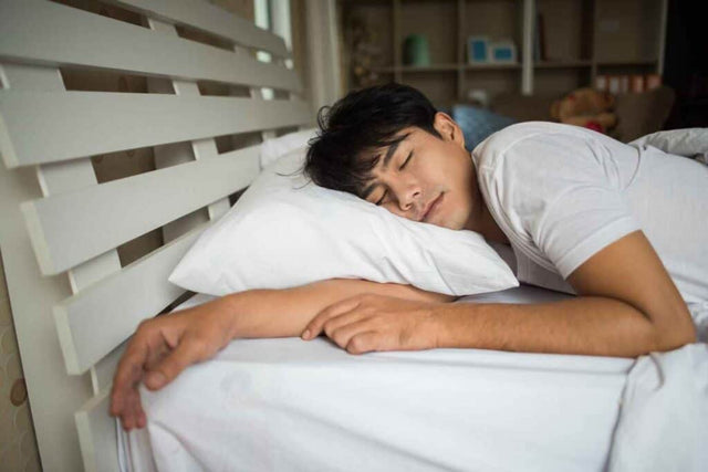 REM Sleep คืออะไร?: ผู้ชายกำลังนอนหลับพักผ่อนบนเตียง